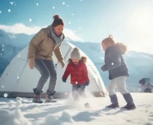 Mother and children playing in the snow near a tent during a winter camping trip