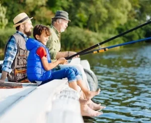 Three generations fishing together on a dock by a lake