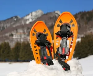 Bright orange snowshoes in the snow with a hilly Duluth landscape, rented from North Sport Rentals