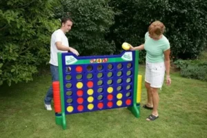 Two people playing a giant Connect 4 game outdoors, available for rent at North Sport Rentals.