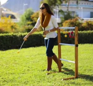 Woman playing an outdoor ladder golf game on a sunny day, available for rent at North Sport Rentals