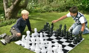 Two boys playing a giant chess game on a lawn, available for rent at North Sport Rentals