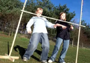 Two children playing a giant limbo game outdoors on a sunny day, available at North Sport Rentals