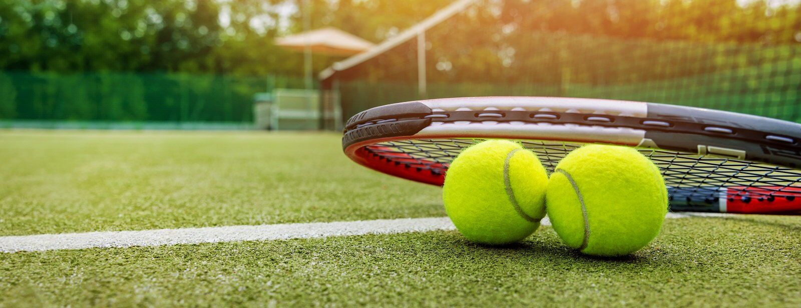 Tennis racket and ball on green grass court