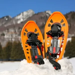 Bright orange snowshoes in the snow with a hilly Duluth landscape, rented from North Sport Rentals