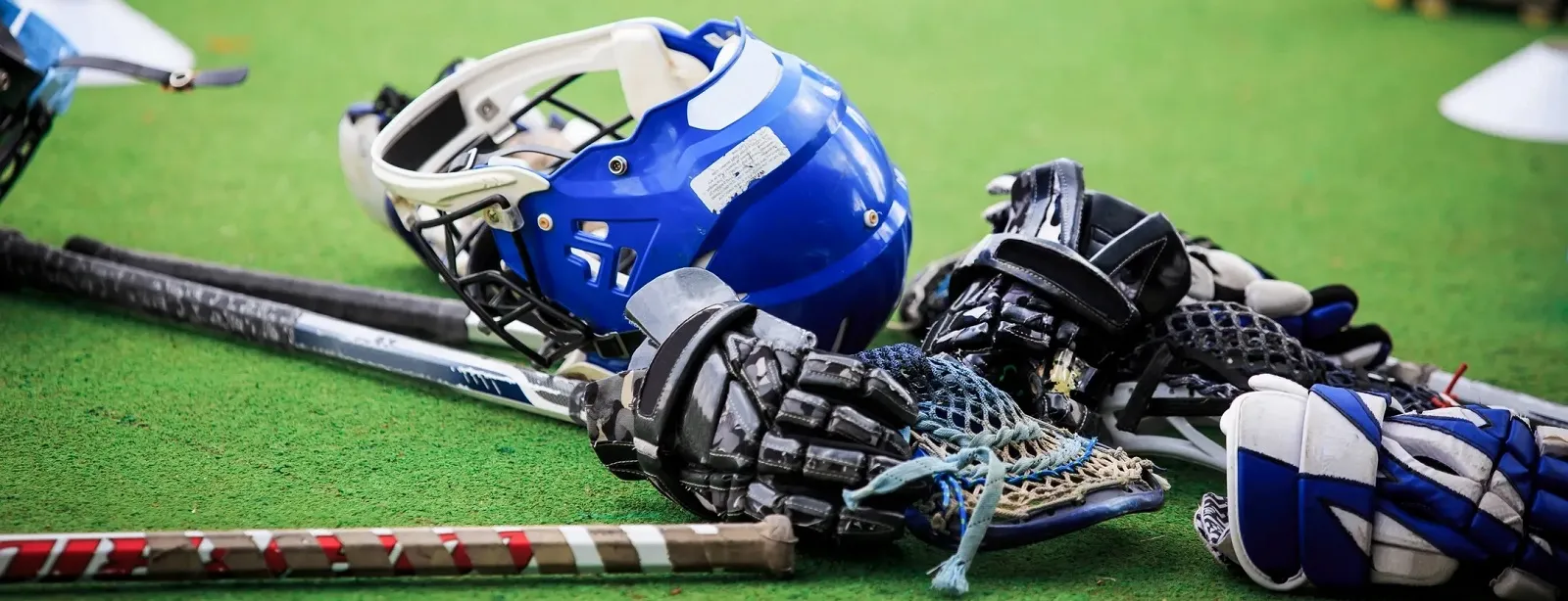 Lacrosse helmet, gloves, and sticks on a field, representing North Sport Rentals' lacrosse corporate rentals for team-building events in Minnesota.