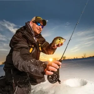 Ice fisherman holding a fish during sunset on a frozen lake, North Sport Rentals in Minnesota