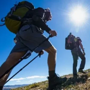 Two hikers with trekking poles hiking uphill on a sunny day in Minnesota