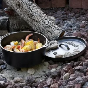 Cast iron Dutch oven cooking a campfire seafood boil, ideal for outdoor meals, available from North Sport Rentals in Minnesota