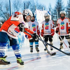 Junior and youth players practicing ice hockey outdoors, wearing rental gear.