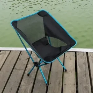 Compact black camping chair set up on a wooden dock by a calm lake, available for rent in Minnesota areas like Minneapolis and Bloomington