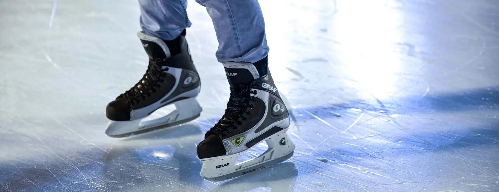 Close-up of a pair of ice skates on a shiny ice rink, featuring high-quality ice skate rentals for all skill levels.