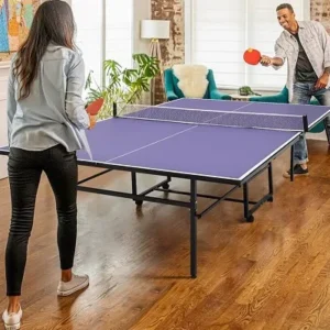 A couple playing an intense game of ping pong indoors in a cozy living room with bright decor.