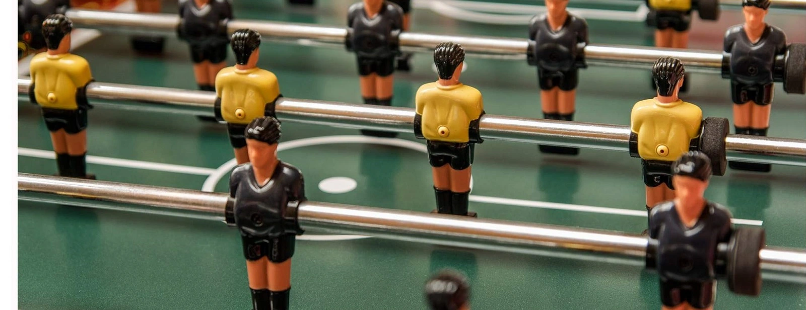 Close-up of a foosball table with yellow and black team players, perfect for foosball table rentals for events and gatherings.