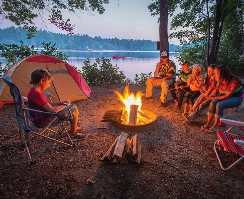 Family camping gear rental setup with fire pit, tent, and chairs outdoors